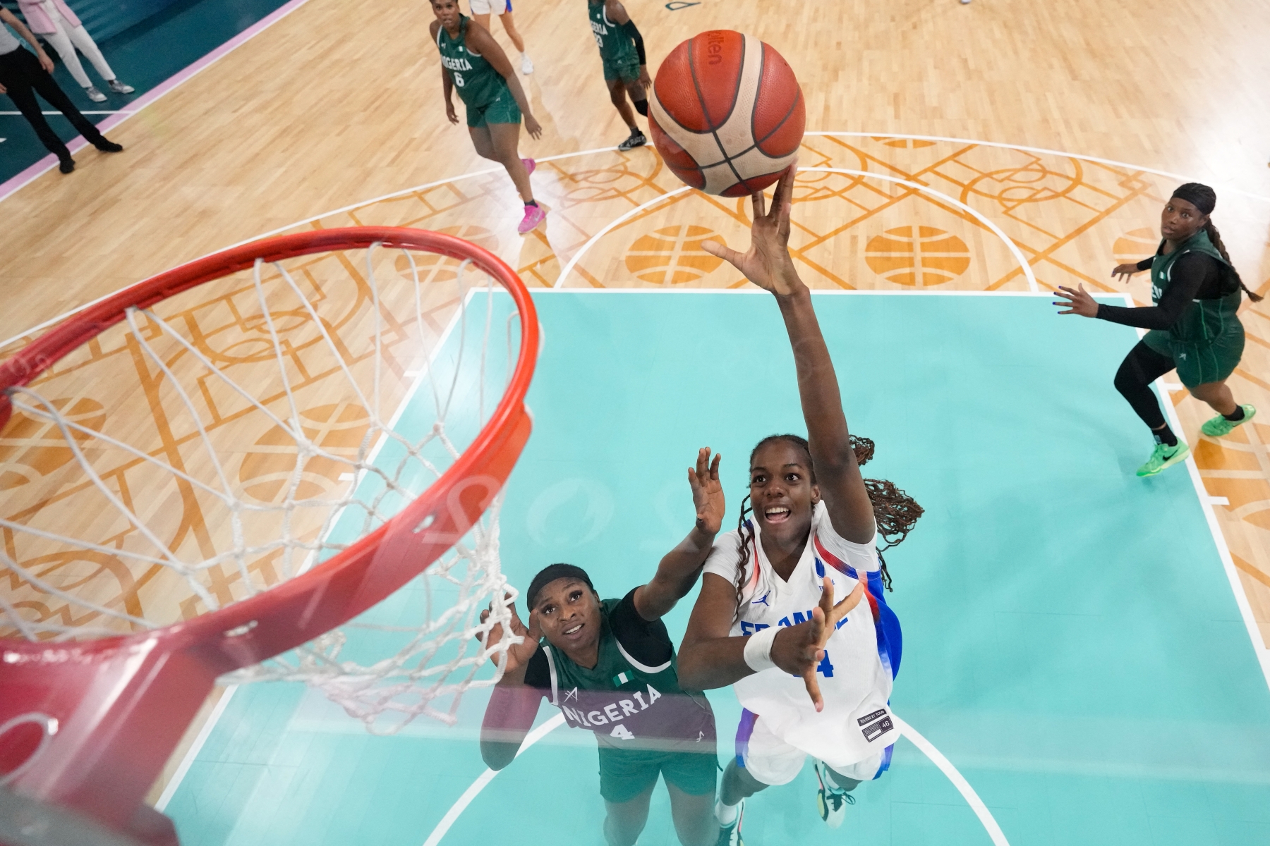 French basketball player Dominique Malonga takes flight in the paint and towards the rim holding the ball in her left hand as Nigerian defender Elizabeth Balogun defends her with a hand near Malonga's face